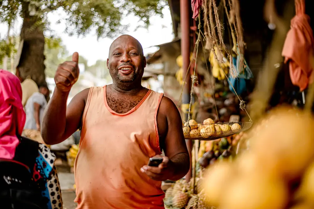 A fruit seller giving a thumbs up at his stall