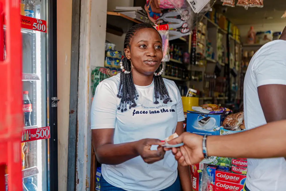 A shop owner in Dar es Salaam smiling as she takes a payment
