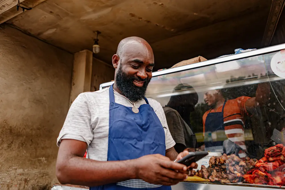 A street food vendor smiling at his phone
